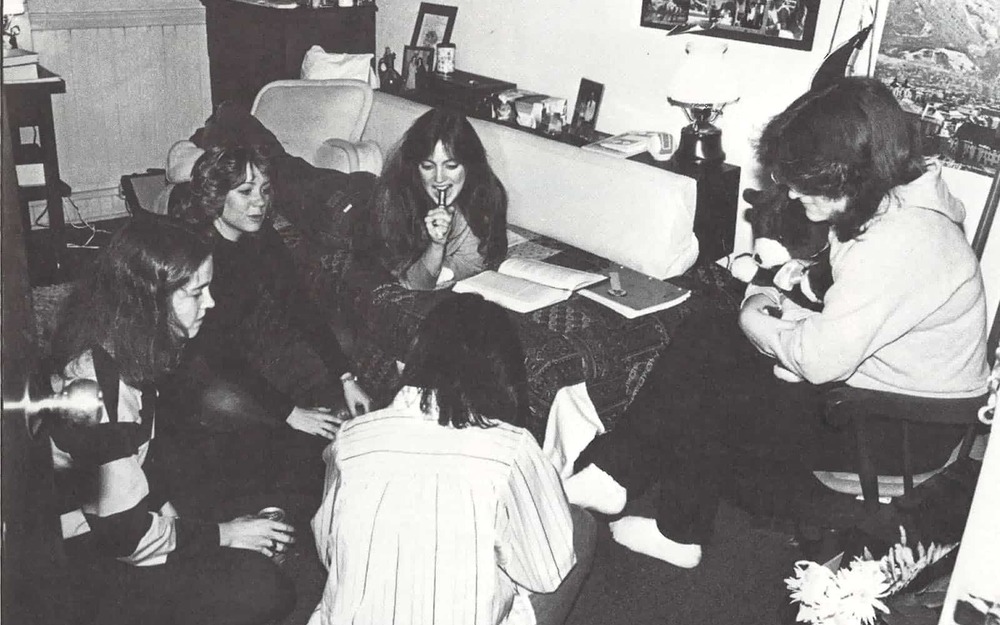 Five women lounge inside their dorm room.