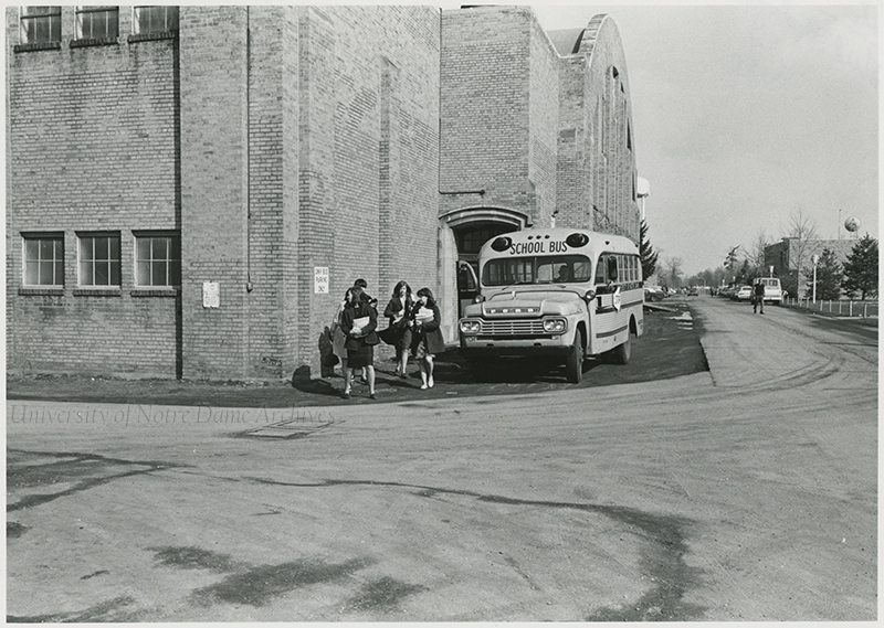 Women students exit a school bus on Notre Dame's campus.
